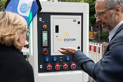 Mann präsentiert Dame die Speicherlösung Voltstation